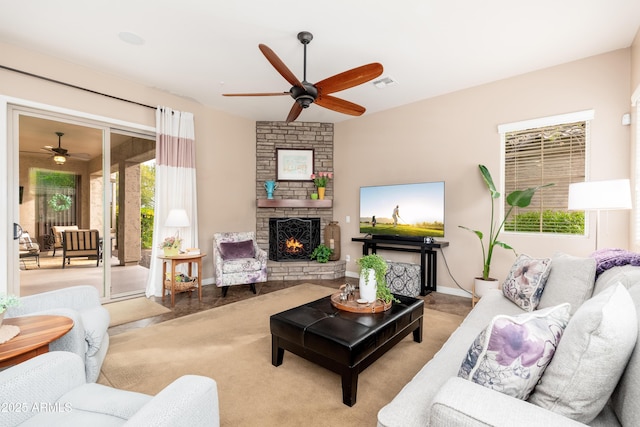 carpeted living room with visible vents, a ceiling fan, and a stone fireplace
