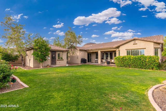 back of house featuring a lawn, stucco siding, a patio area, and a tile roof