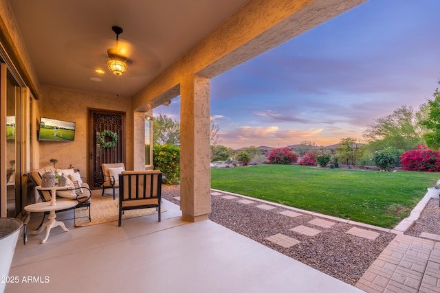 patio terrace at dusk featuring a lawn