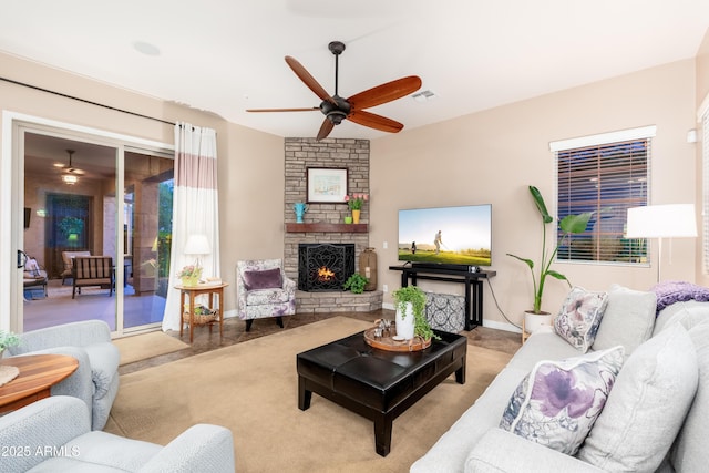 living room featuring ceiling fan, visible vents, baseboards, and a fireplace