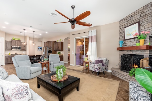 living area featuring ceiling fan, a fireplace, arched walkways, recessed lighting, and visible vents