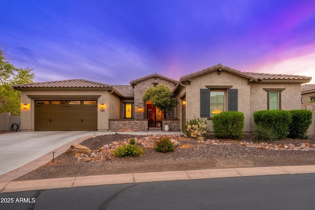 mediterranean / spanish house with a tiled roof, an attached garage, driveway, and stucco siding