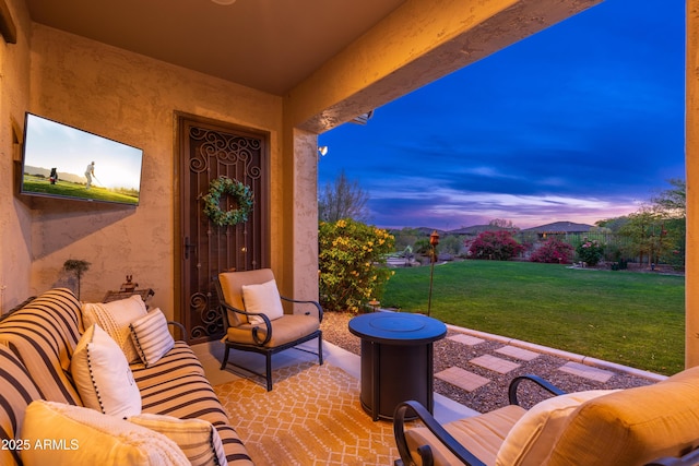 patio terrace at dusk featuring a lawn and outdoor lounge area