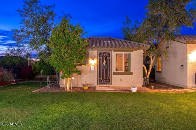view of front of house with an outdoor structure, a tiled roof, stucco siding, and a front yard