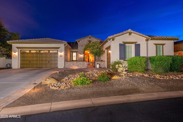 mediterranean / spanish home featuring a garage, stucco siding, concrete driveway, and a tiled roof