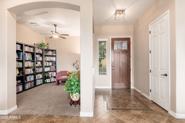 carpeted foyer entrance with baseboards, a ceiling fan, and visible vents