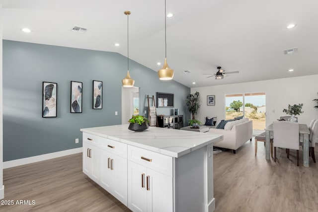 kitchen featuring light wood-style flooring, visible vents, vaulted ceiling, and light stone countertops