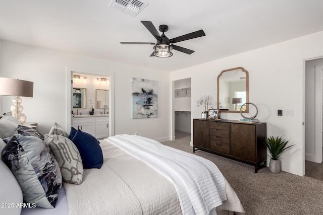 carpeted bedroom with a walk in closet, ensuite bathroom, visible vents, a ceiling fan, and a closet