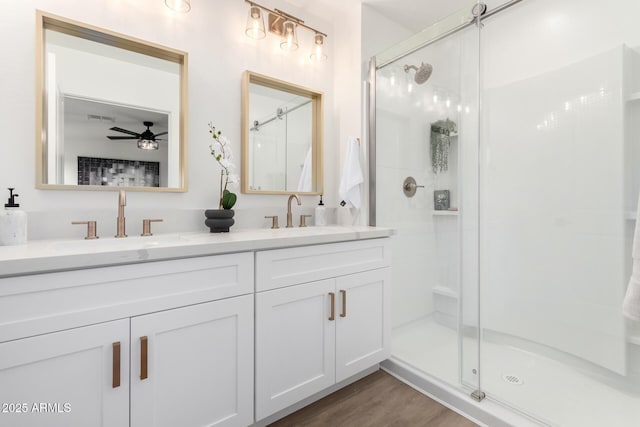 full bathroom featuring double vanity, ceiling fan, a sink, and a stall shower