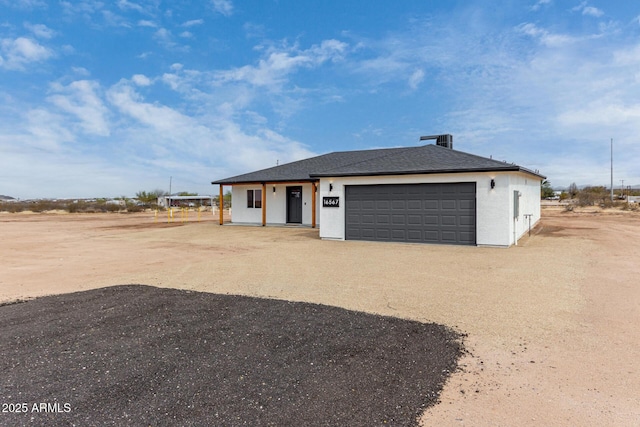 view of front of house with driveway, an attached garage, stucco siding, and roof with shingles