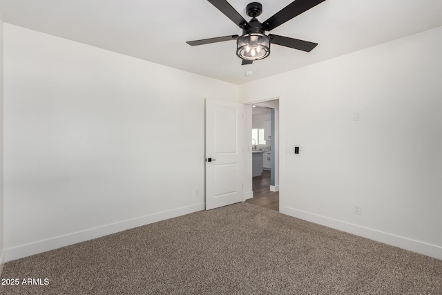 carpeted spare room with a ceiling fan and baseboards