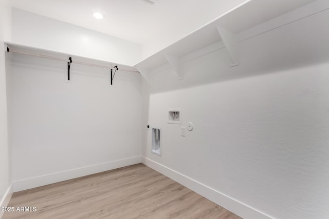 clothes washing area with light wood finished floors, baseboards, hookup for a gas dryer, and laundry area