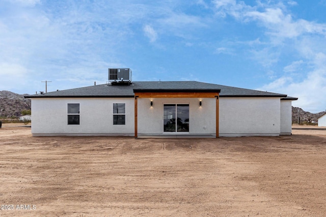 rear view of house featuring central AC unit, a shingled roof, and a mountain view