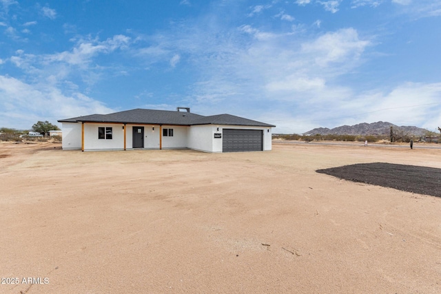 view of front facade with dirt driveway, a garage, and a mountain view