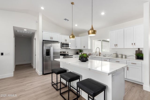 kitchen featuring visible vents, a kitchen bar, a kitchen island, appliances with stainless steel finishes, and white cabinetry