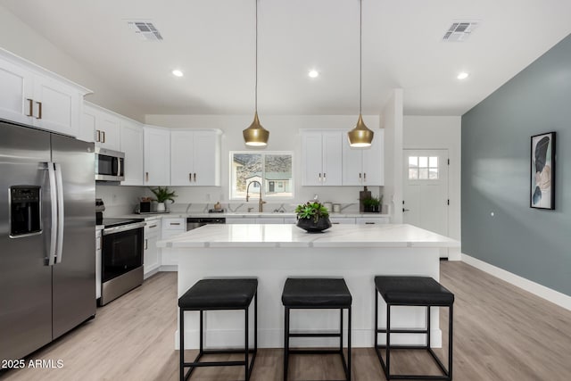 kitchen with a kitchen bar, a sink, appliances with stainless steel finishes, and visible vents
