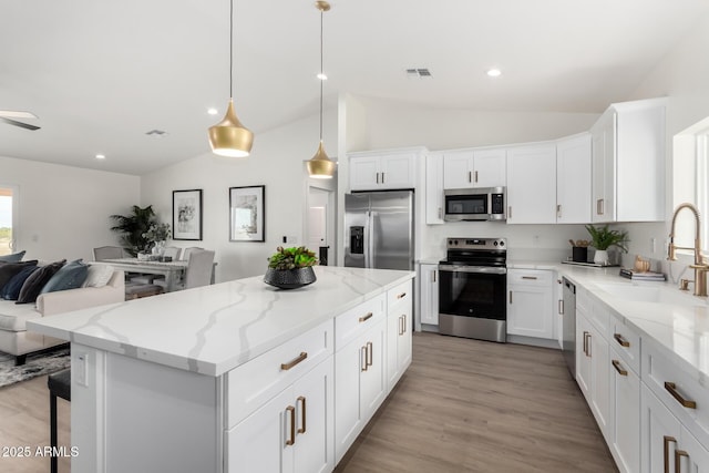 kitchen with visible vents, stainless steel appliances, a sink, open floor plan, and vaulted ceiling