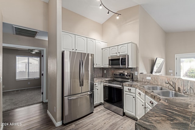 kitchen with sink, white cabinetry, stainless steel appliances, and light hardwood / wood-style flooring