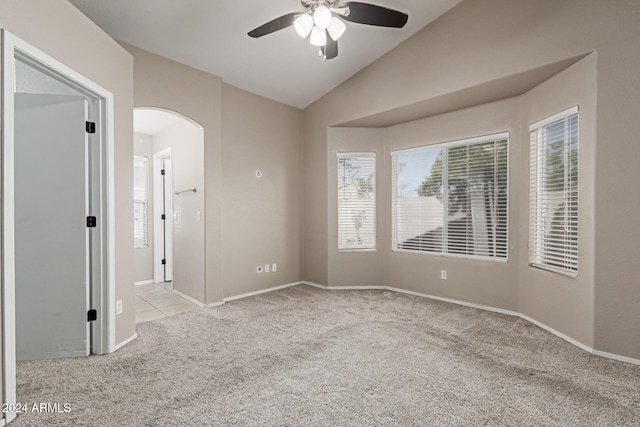 carpeted spare room featuring vaulted ceiling and ceiling fan