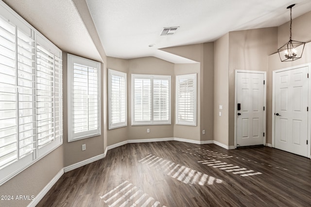 foyer entrance with dark hardwood / wood-style flooring, a textured ceiling, and an inviting chandelier