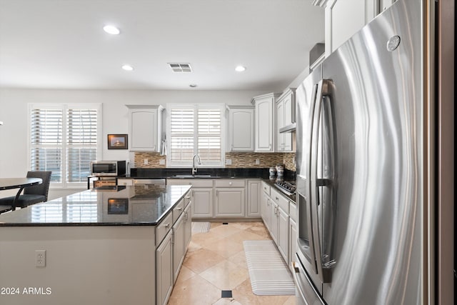 kitchen with appliances with stainless steel finishes, a healthy amount of sunlight, a sink, and a center island