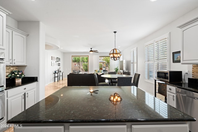 kitchen with stainless steel appliances, open floor plan, white cabinetry, and a kitchen island