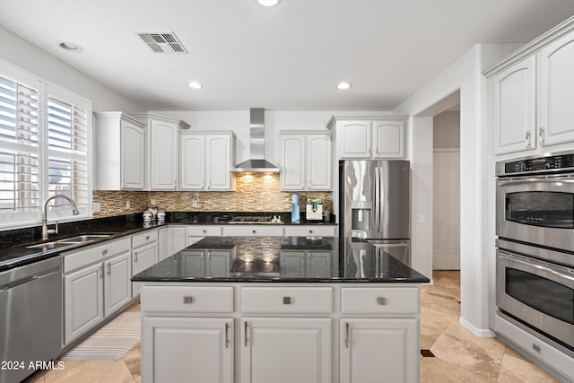 kitchen with visible vents, white cabinets, stainless steel appliances, wall chimney range hood, and a sink