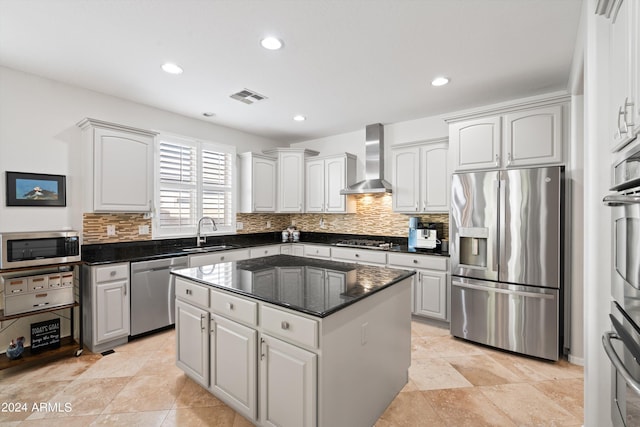 kitchen with stainless steel appliances, visible vents, a kitchen island, wall chimney range hood, and a sink