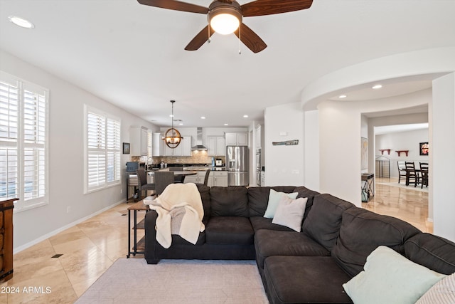 living area with light tile patterned floors, ceiling fan with notable chandelier, baseboards, and recessed lighting