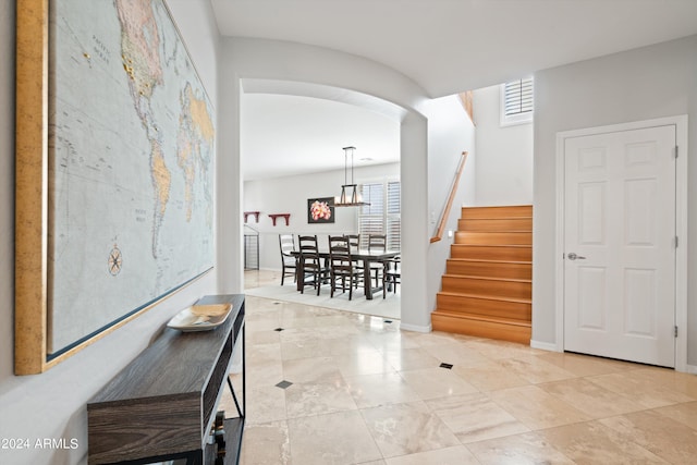 hallway with a healthy amount of sunlight, baseboards, stairway, and arched walkways