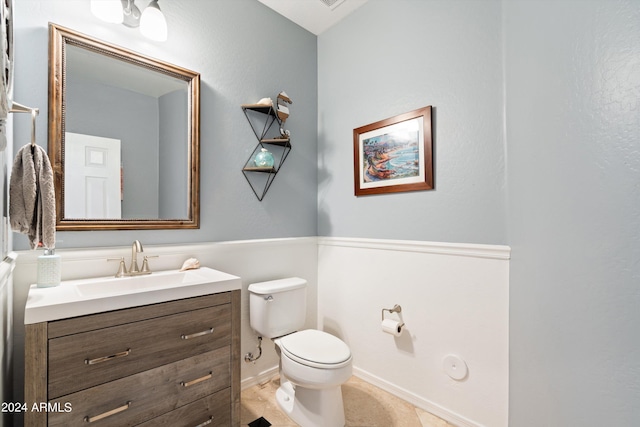 half bathroom with tile patterned flooring, baseboards, vanity, and toilet