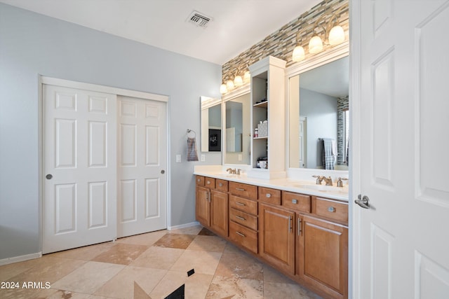 full bath with double vanity, baseboards, visible vents, and a sink