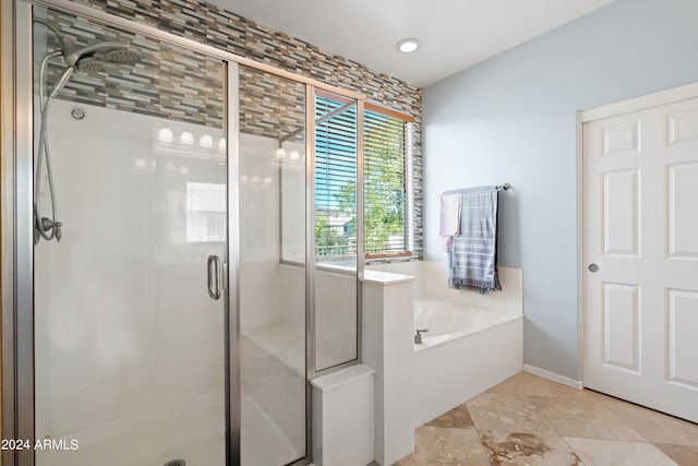 bathroom featuring a stall shower, a garden tub, and baseboards