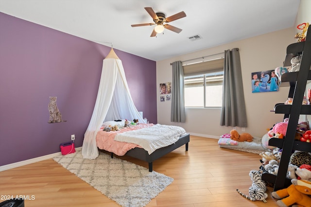 bedroom featuring light wood finished floors, baseboards, visible vents, and a ceiling fan