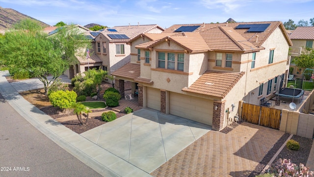 view of front of house featuring a tile roof, stucco siding, roof mounted solar panels, fence, and stone siding