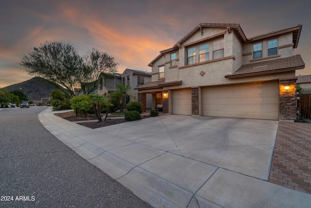 view of front of home with a garage, stone siding, driveway, and a mountain view