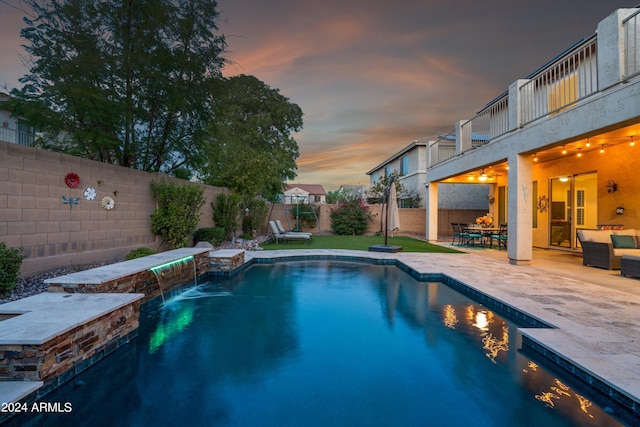 pool at dusk featuring a patio area, a fenced backyard, and a fenced in pool