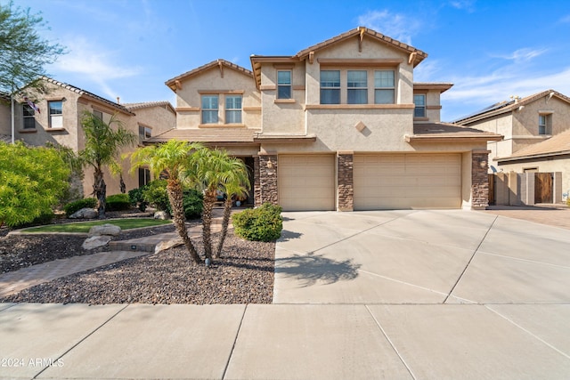 view of front of property with concrete driveway, stone siding, a tile roof, an attached garage, and stucco siding