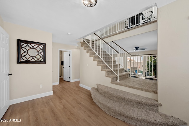 staircase featuring ceiling fan and wood-type flooring