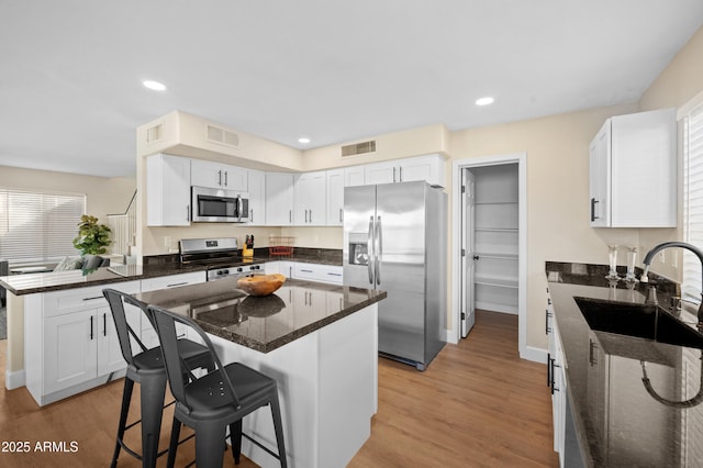 kitchen with sink, white cabinetry, a breakfast bar area, and appliances with stainless steel finishes