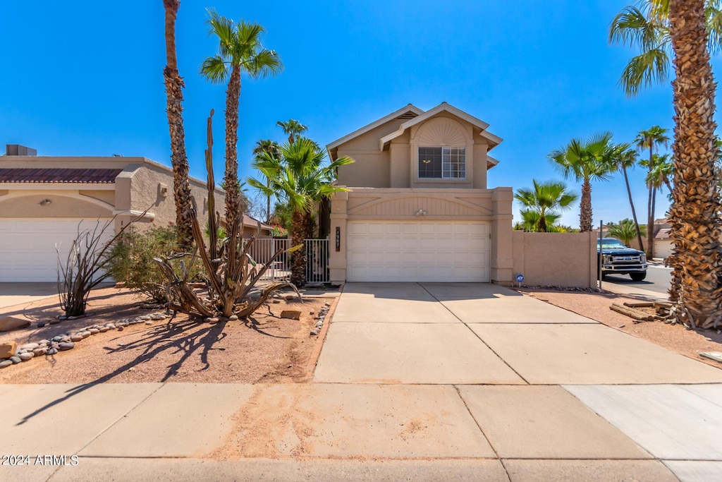 view of front facade featuring a gate, fence, driveway, an attached garage, and stucco siding