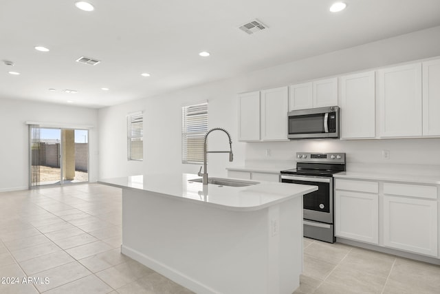 kitchen featuring white cabinets, sink, stainless steel appliances, and a kitchen island with sink