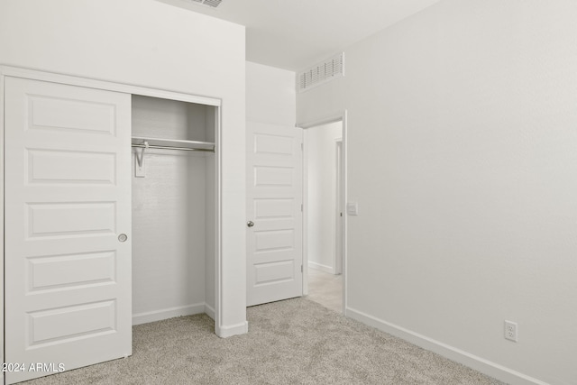 unfurnished bedroom featuring light carpet and a closet