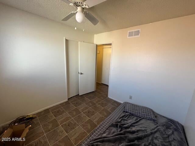 bedroom with ceiling fan and a textured ceiling