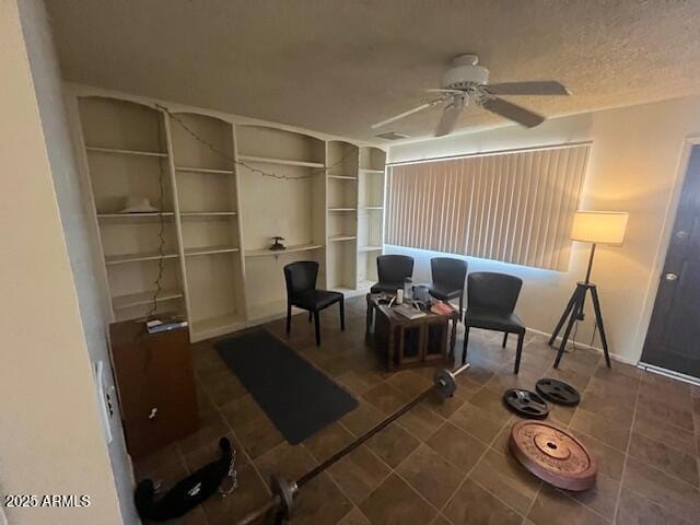 living area with ceiling fan, a textured ceiling, and dark tile patterned flooring