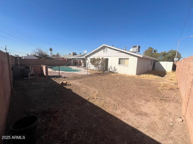 rear view of property featuring a fenced in pool