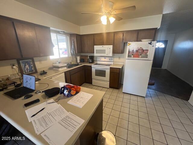 kitchen featuring light tile patterned flooring, dark brown cabinets, sink, and white appliances