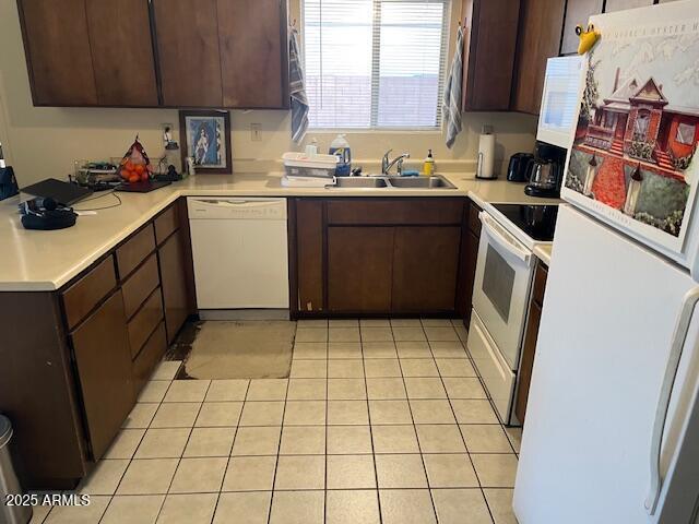 kitchen featuring dark brown cabinetry, sink, white appliances, and light tile patterned floors