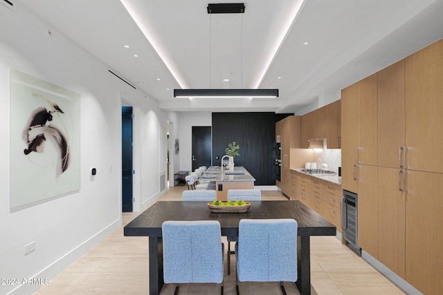 tiled dining space featuring sink, beverage cooler, and a tray ceiling