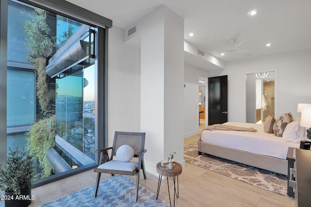 bedroom with ceiling fan, a wall of windows, ensuite bathroom, and multiple windows